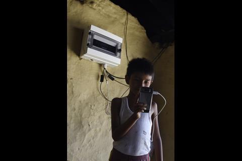 Image of a young boy half in shadow charging his phone